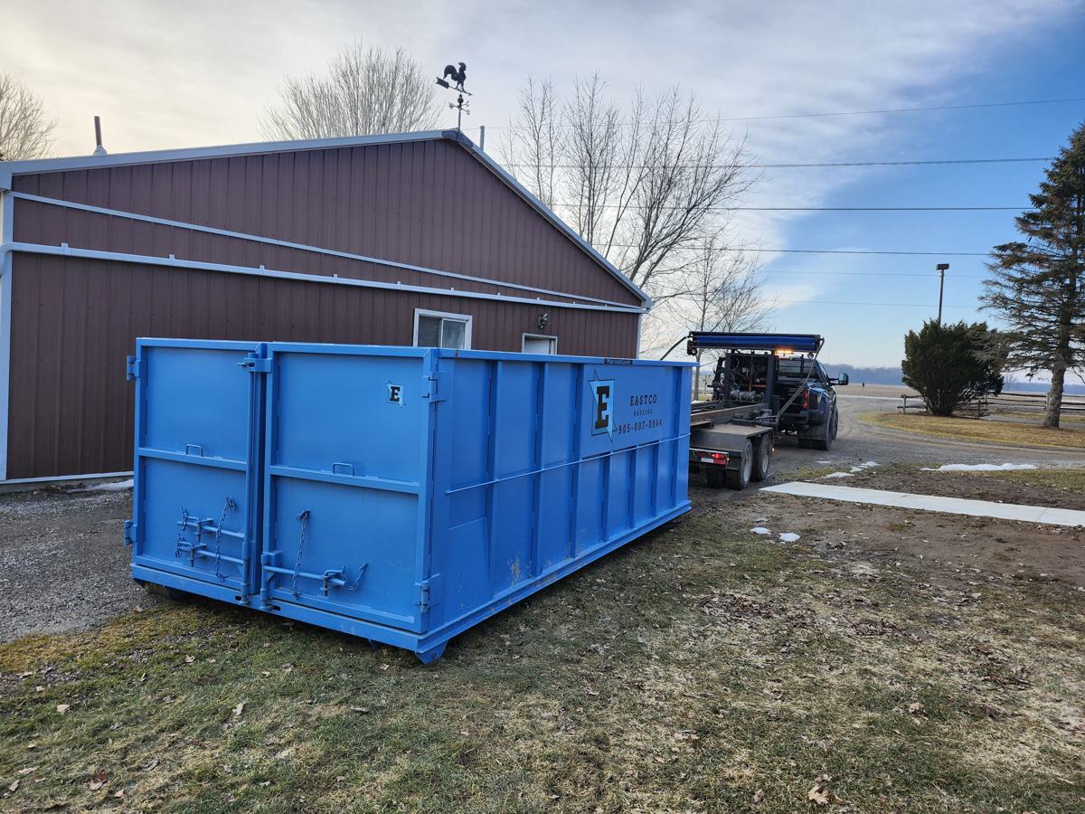Eastco Hauling roll-off bin on site, with truck in the background